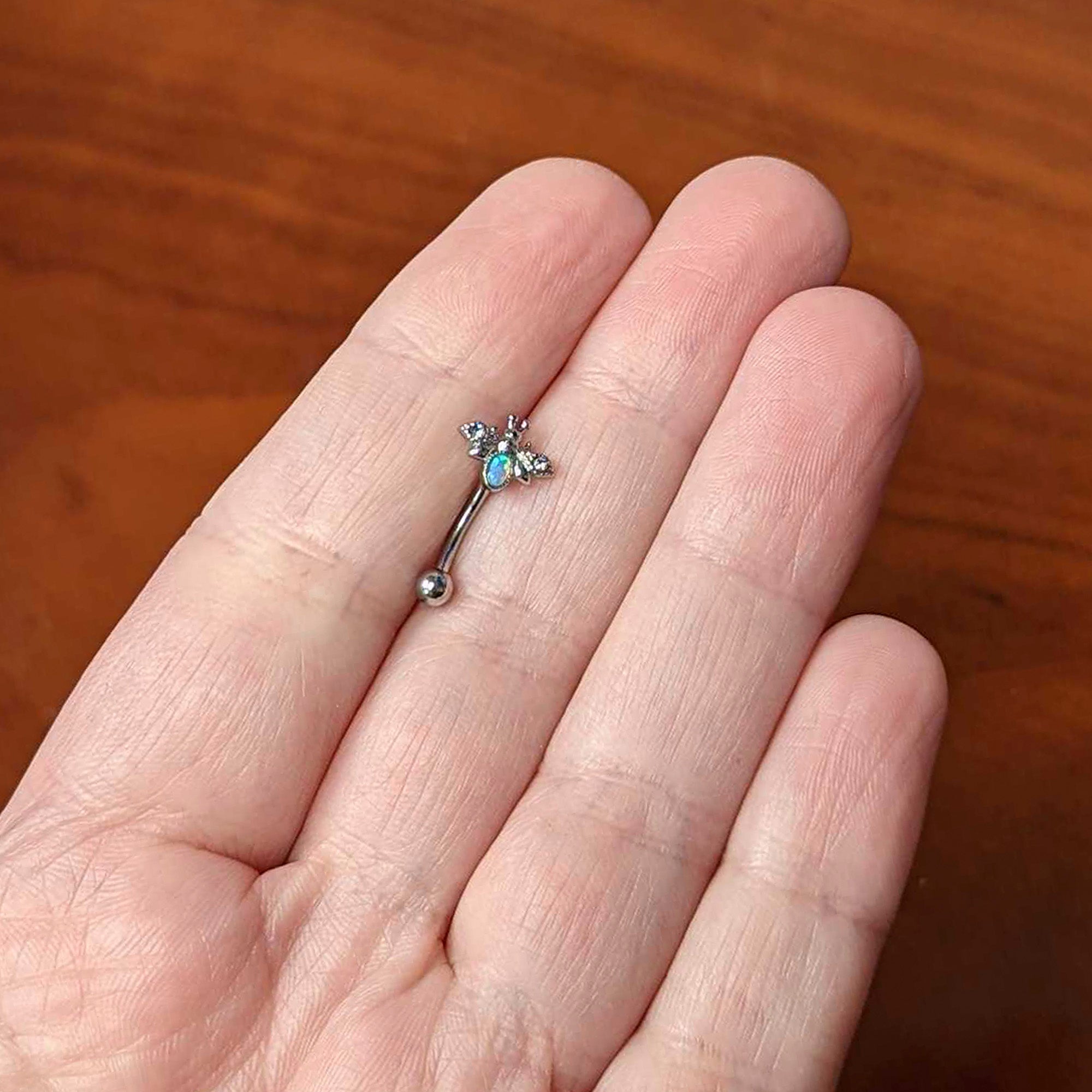 BodyCandy 16G 5/16 White Synthetic Opal Insect Curved Eyebrow Ring — lifestyle context