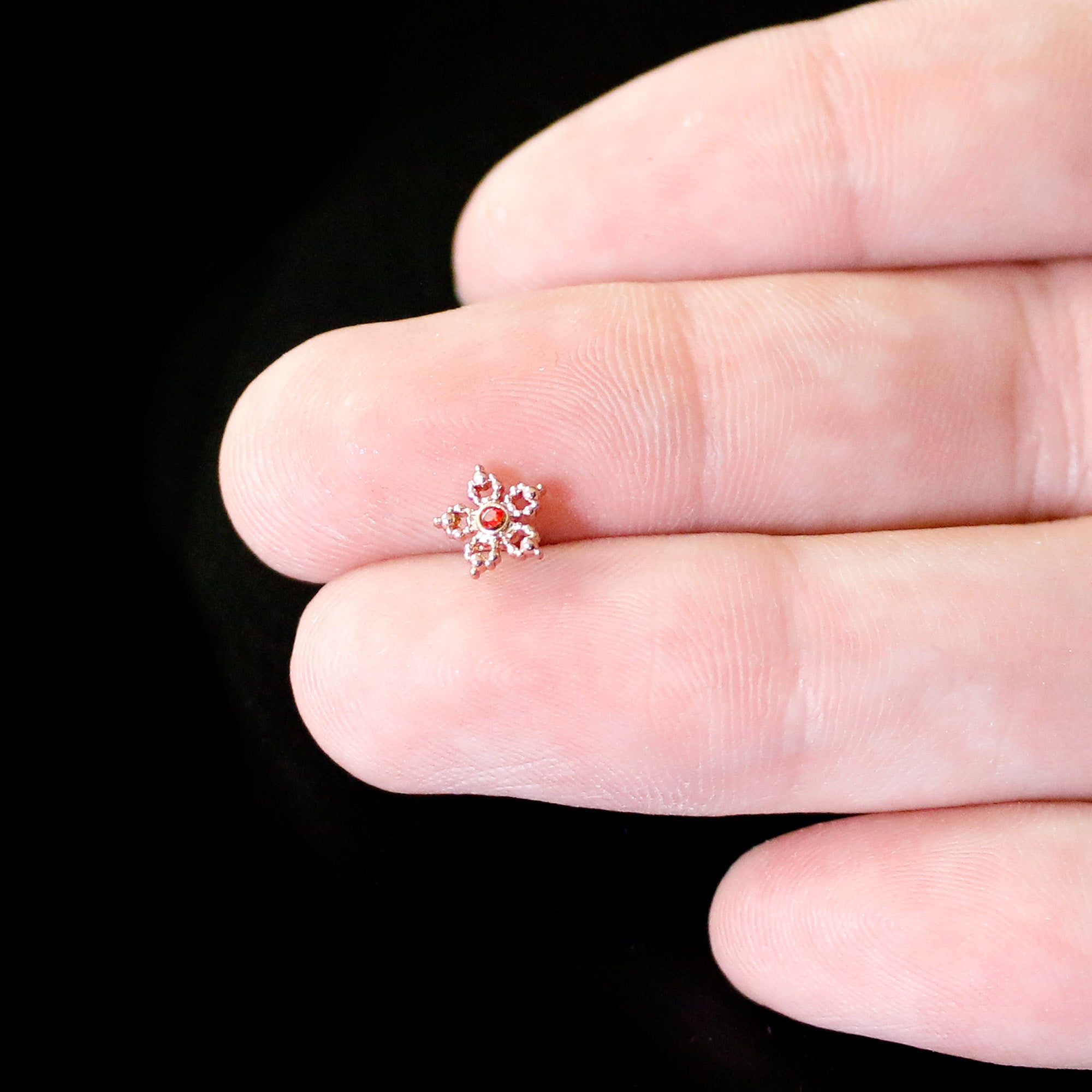 BodyCandy 20G 1/4 Red Gem Rose Gold Tone Textured Snowflake Nose Bone — in-use photo