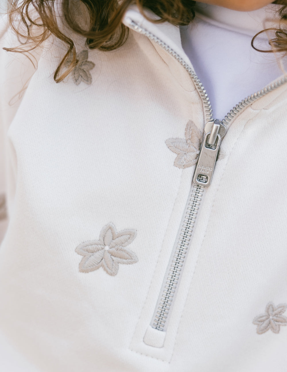 Elevated Faith Floral Kids Half-Zip — Elevated Faith branding close-up