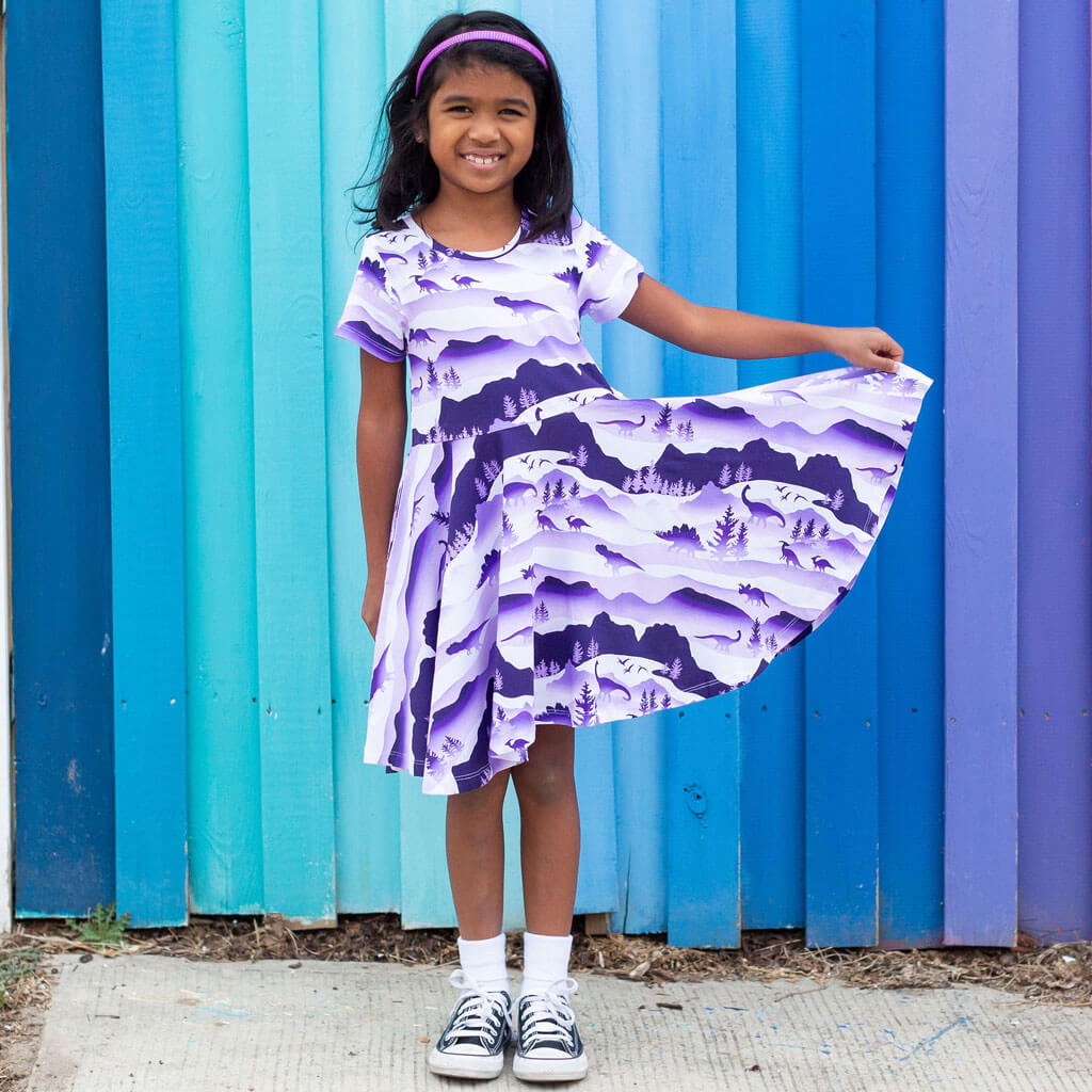 Princess Awesome & Boy Wonder "Dinoscape" Dinosaur Wilderness Super Twirler Dress with Pockets — Princess Awesome & Boy Wonder branding close-up